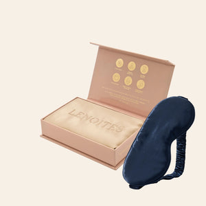 Pillowcase and Sleep Mask in Mulberry Silk by Lenoites featuring a blue silk sleep mask and a beige mulberry silk pillowcase presented in an open blush pink box against a soft light background.