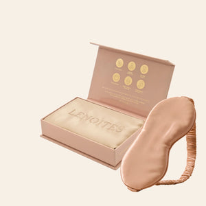 Pillowcase and Sleep Mask in Mulberry Silk by Lenoites featuring a rosegold silk sleep mask and a beige mulberry silk pillowcase presented in an open blush pink box against a soft light background.
