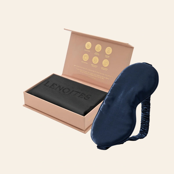 Pillowcase and Sleep Mask in Mulberry Silk by Lenoites featuring a blue silk sleep mask and a black mulberry silk pillowcase presented in an open blush pink box against a soft light background.