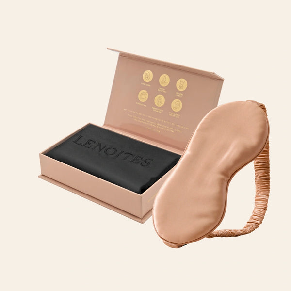 Pillowcase and Sleep Mask in Mulberry Silk by Lenoites featuring a rosegold silk sleep mask and a black mulberry silk pillowcase presented in an open blush pink box against a soft light background.