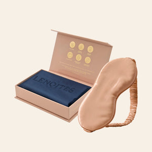 Pillowcase and Sleep Mask in Mulberry Silk by Lenoites featuring a rosegold silk sleep mask and a blue mulberry silk pillowcase presented in an open blush pink box against a soft light background.
