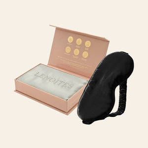Pillowcase and Sleep Mask in Mulberry Silk by Lenoites featuring a black silk sleep mask and a grey mulberry silk pillowcase presented in an open blush pink box against a soft light background.