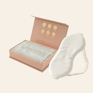 Pillowcase and Sleep Mask in Mulberry Silk by Lenoites featuring a white silk sleep mask and a grey mulberry silk pillowcase presented in an open blush pink box against a soft light background.