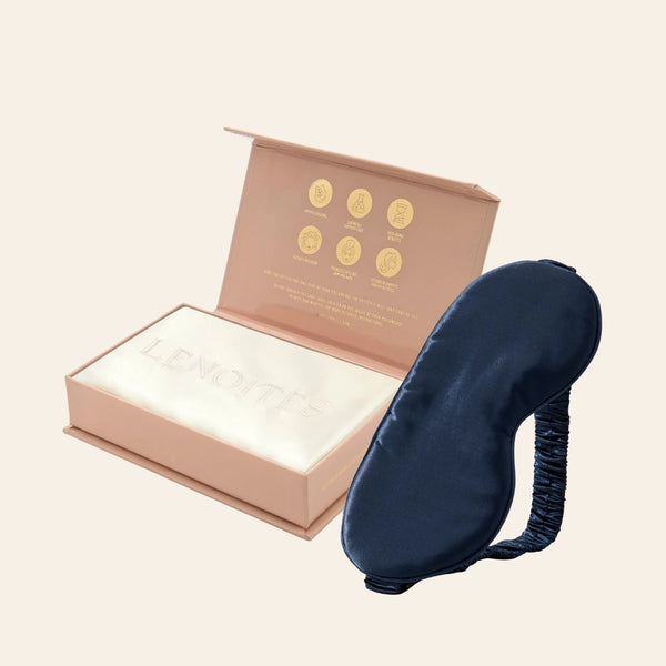 Pillowcase and Sleep Mask in Mulberry Silk by Lenoites featuring a blue silk sleep mask and a white mulberry silk pillowcase presented in an open blush pink box against a soft light background.